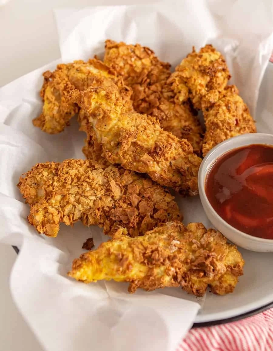 Crispy air fryer chicken tenders on a plate with dipping sauce