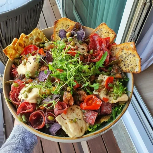 Beach snack charcuterie salad bowl with colorful ingredients and fresh greens