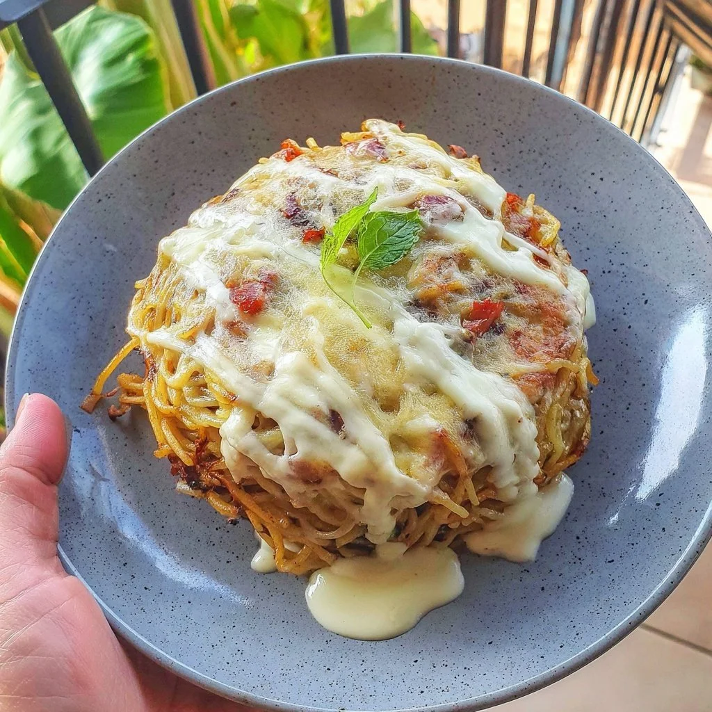 Crispy leftover spaghetti frittata served on a plate with fresh herbs.