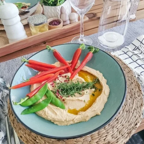 Delicious hummus served with carrots and sweet peas for a healthy appetizer.