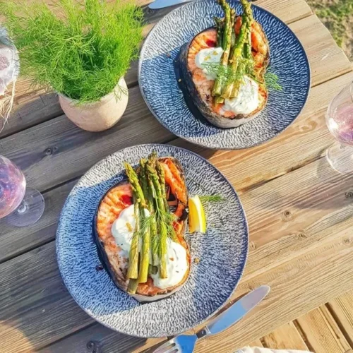 Grilled salmon fillet with asparagus and yogurt-dill sauce on a plate