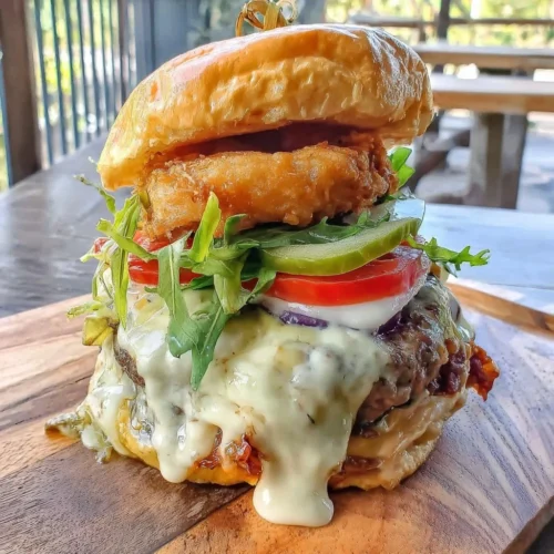 Juicy smash burger drizzled with secret sauce on a wooden platter