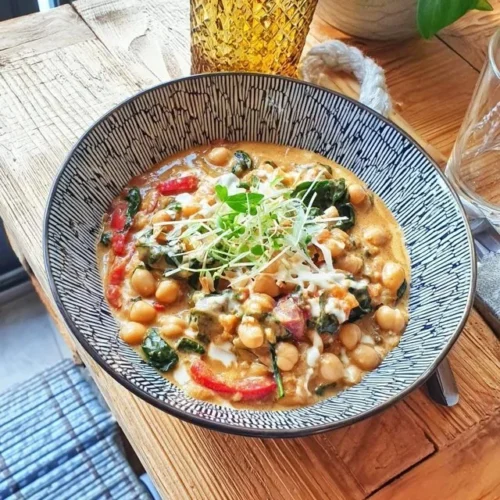 Chickpea coconut and spinach curry served in a bowl with fresh herbs