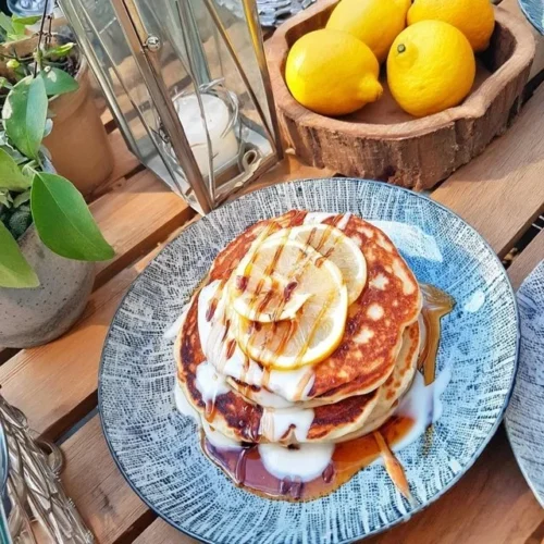 Stack of fluffy Lemon Ricotta Pancakes topped with lemon zest and syrup.
