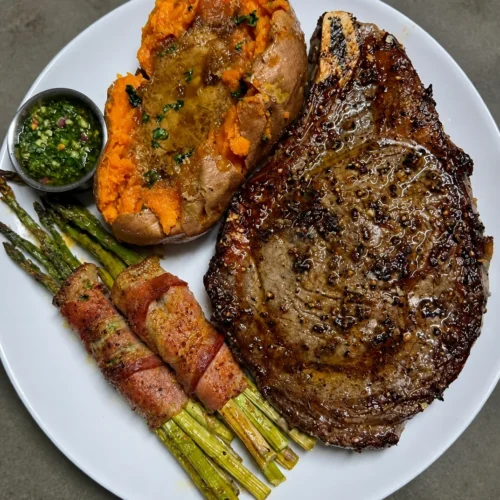 Protein-Packed Bone-in Ribeye with Loaded Sweet Potato, Bacon-Wrapped Asparagus and Crowd-Pleasing Chimichurri